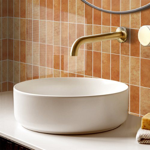 Klebefliesen orange hinter einem Aufsatzwaschbecken mit goldener Armatur