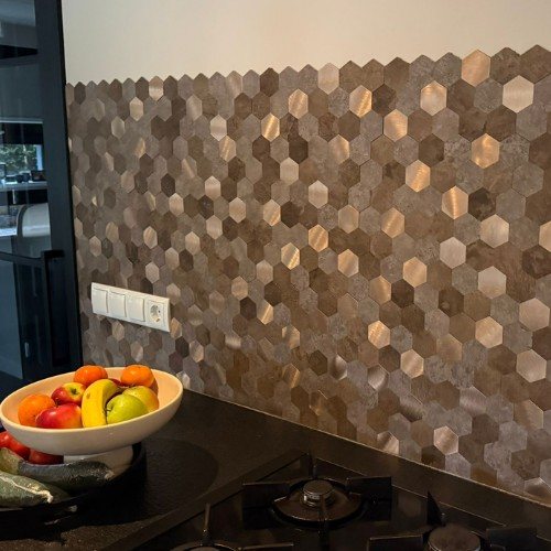 Selbstklebende Mosaikfliesen in Bronze-Metalloptik an der Küchenwand mit Steckdosen